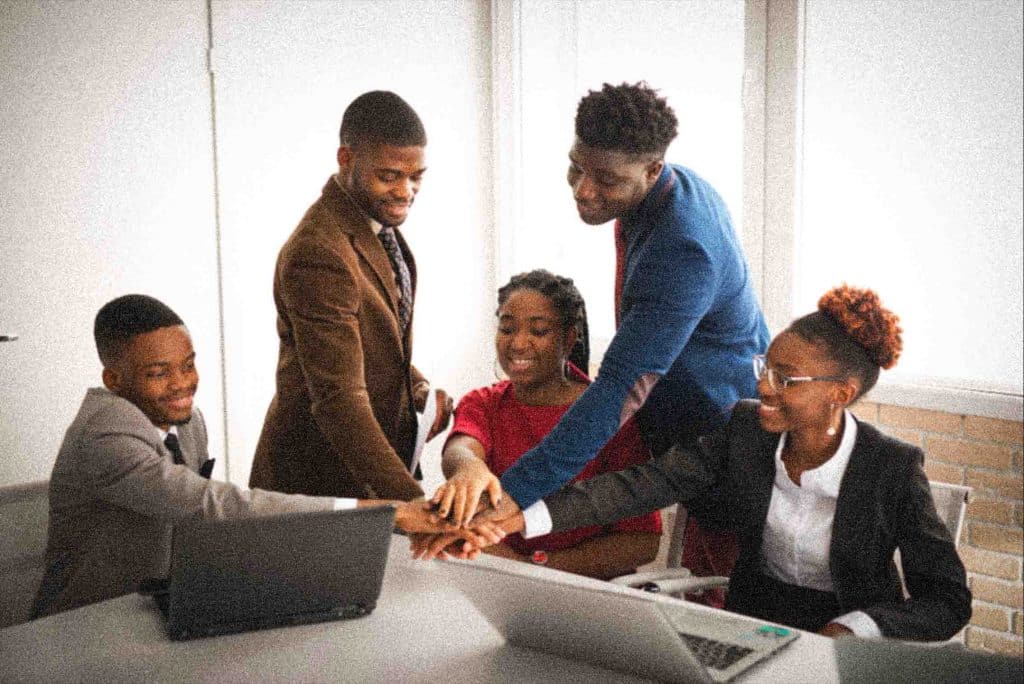 Team of young black people in the office in meeting hands in the middle