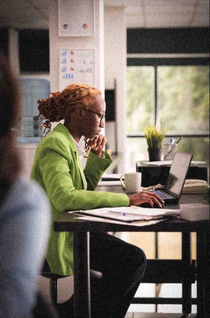 young african american employee focused on her laptop in a coworking office. sitting at desk side view